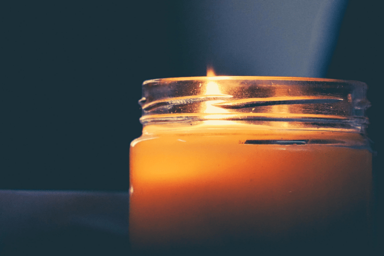 A candle burning in a glass jar