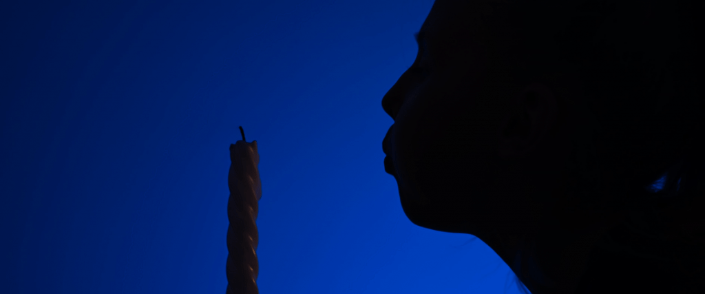 silhouette of person blowing out a candle